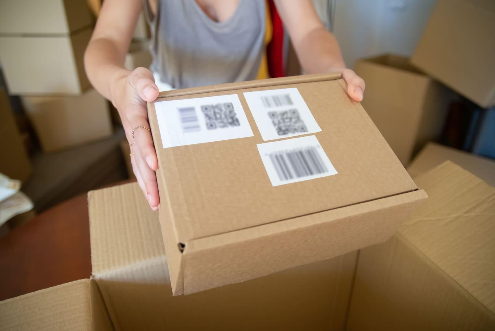 A packed cardboard parcel with barcode labels held ready for dispatch.
